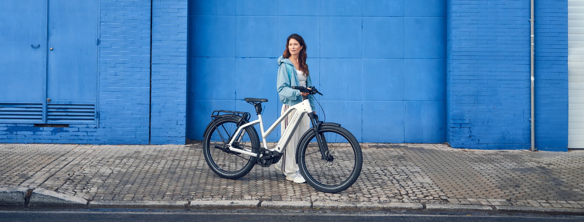 Riese & Müller Charger5 Mixte model year 2026 with a rider by a blue wall